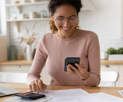 stock photo of a curly-haired woman in glasses smiling and looking down at her phone